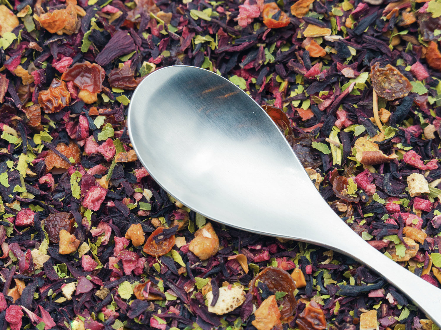 A close up of Slamming Orange fruit tea infusion from TEA23 with a silver spoon resting on top