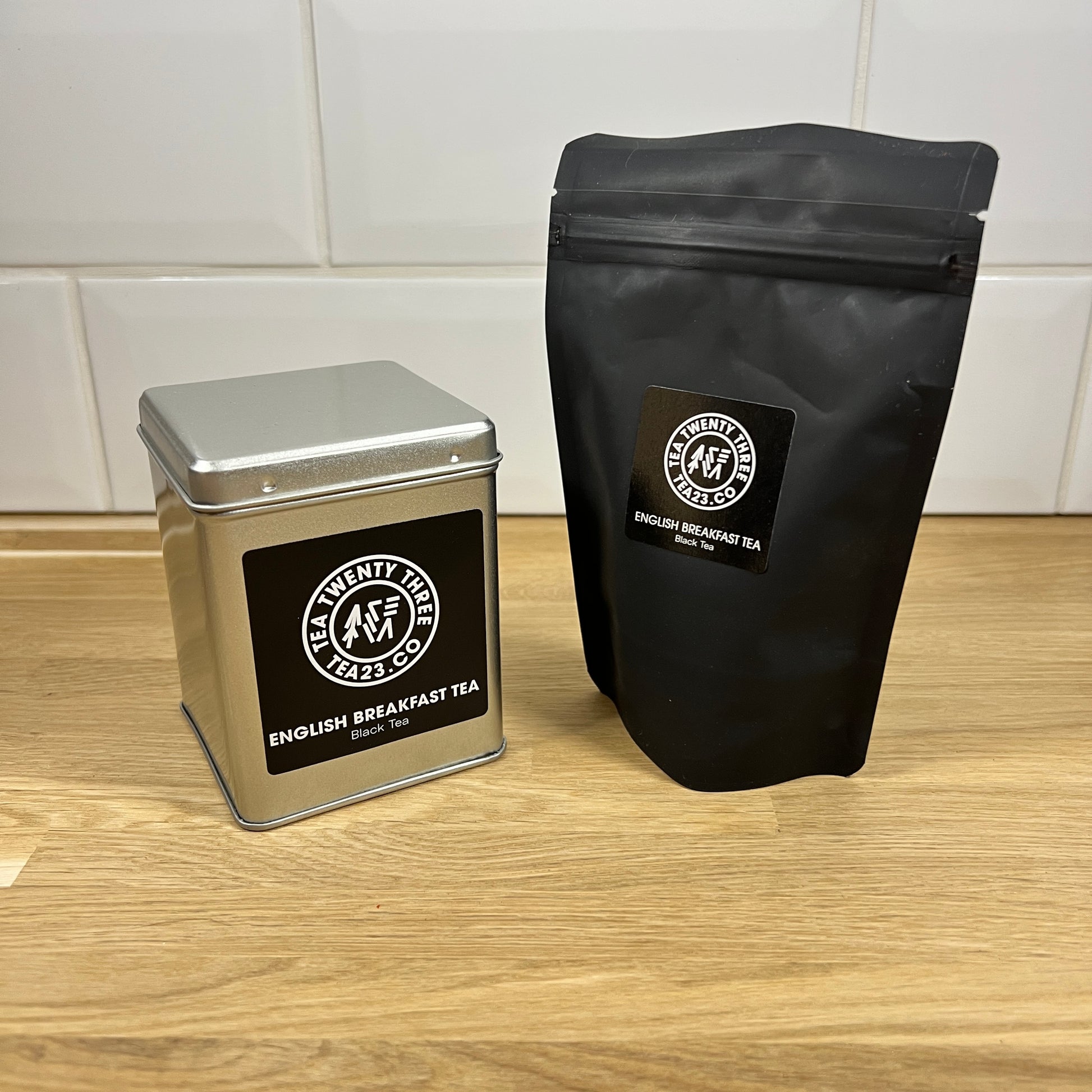 A silver gift tin next to a black pouch of loose leaf English Breakfast Tea