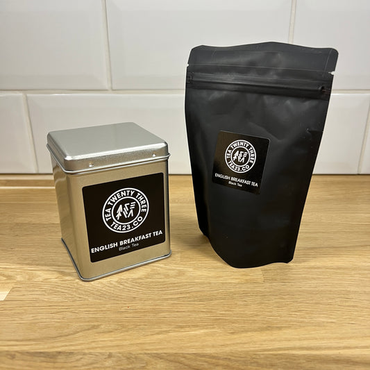 A silver gift tin next to a black pouch of loose leaf English Breakfast Tea