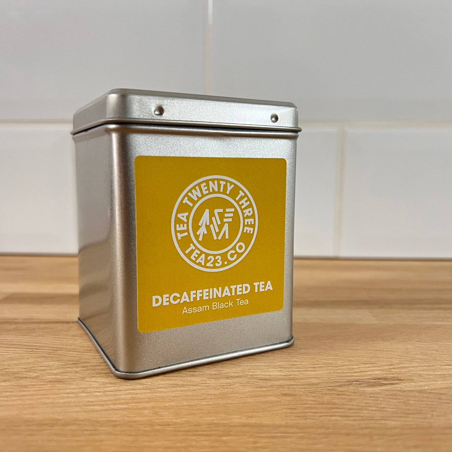 Silver tea canister with a yellow label on a wooden surface