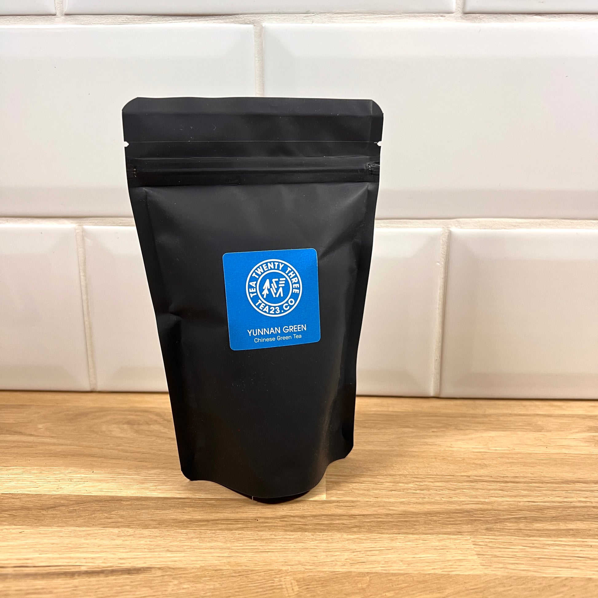 A black pouch of Yunnan Green Tea with a blue label