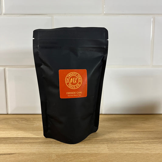 Black tea package with orange label on a wooden surface and white tiled wall background