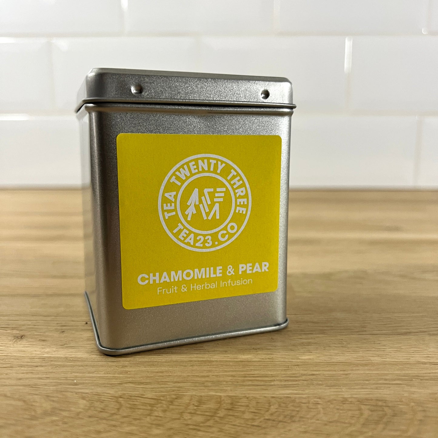 Silver tea tin with a yellow label on a wooden surface