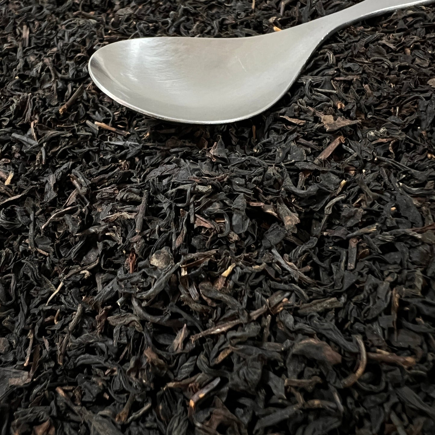 Black tea leaves with a silver spoon on top