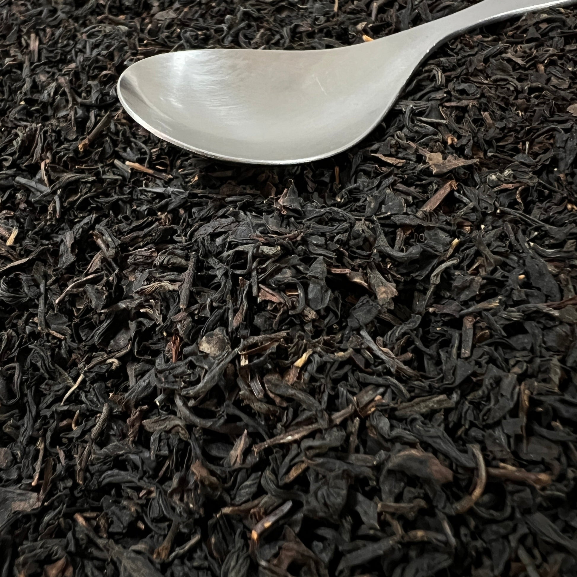 Black tea leaves with a silver spoon on top