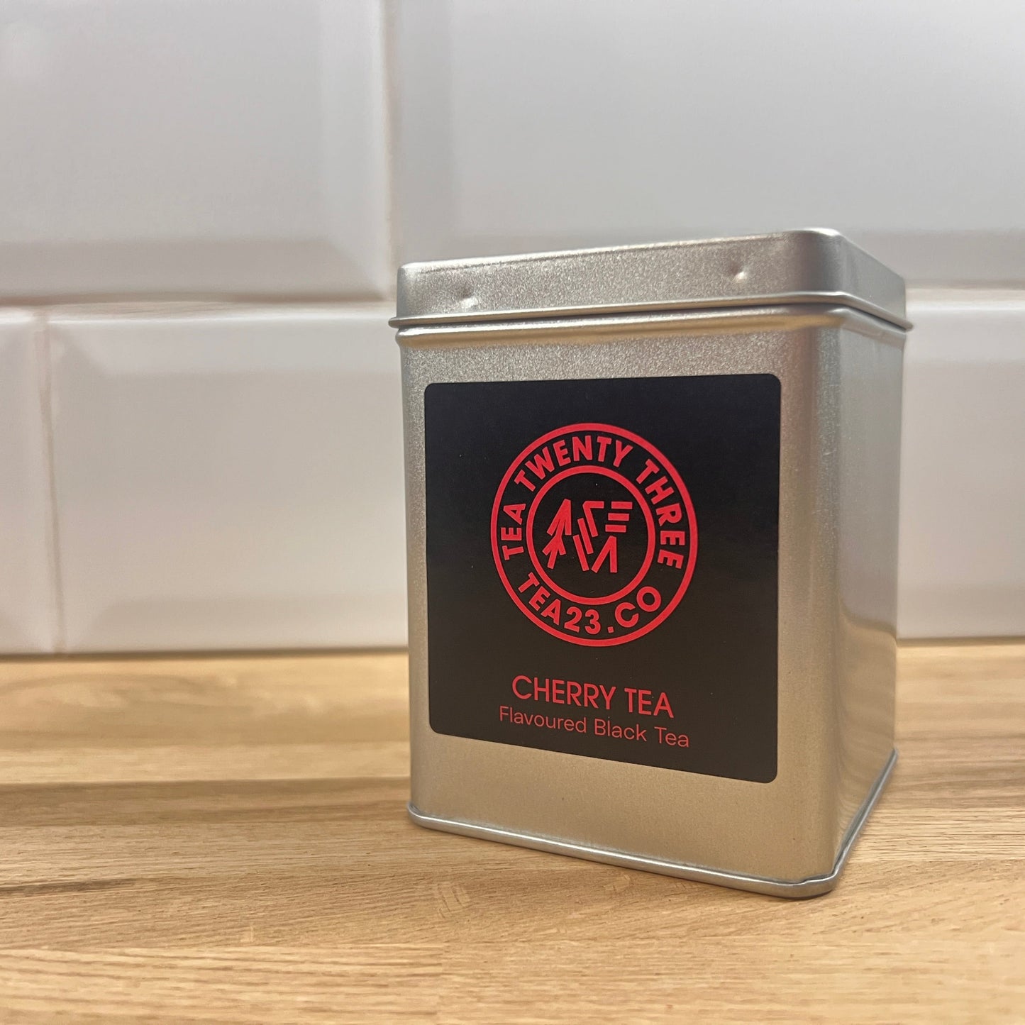 Metal tea canister with 'Tea Twenty Three' label on a wooden surface