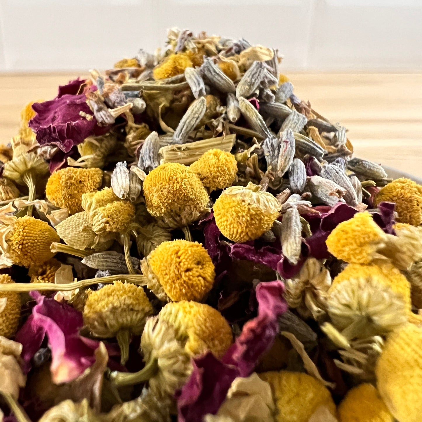 Heap of chamomile, rose petals and lavender on a wooden surface