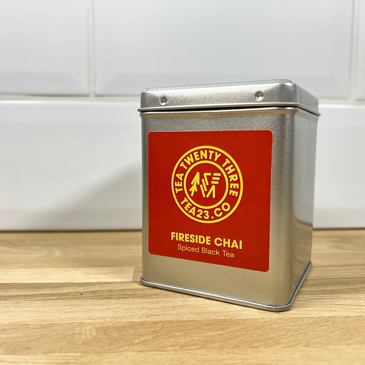 Silver tea canister with a red label on a wooden surface