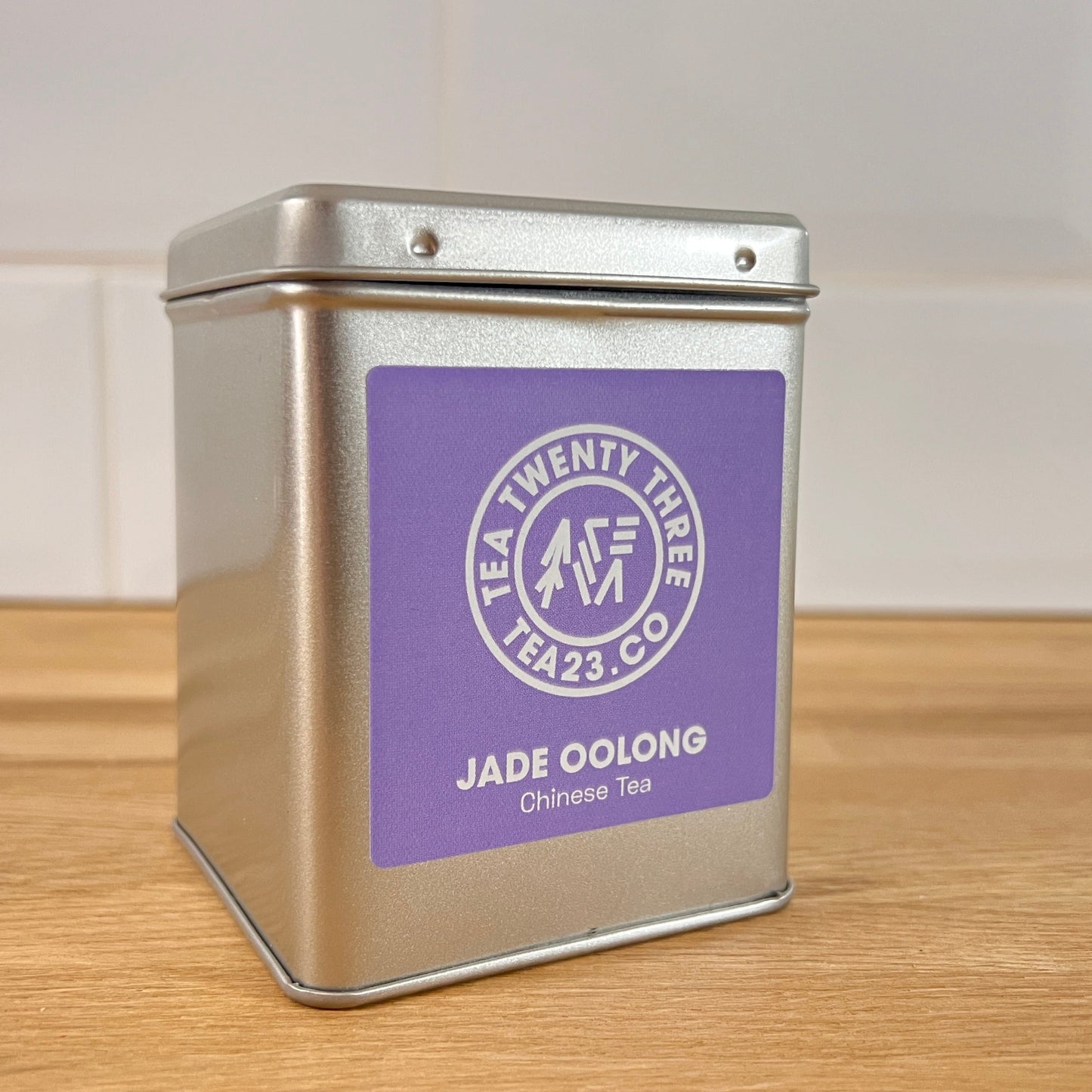 Silver tea tin with a purple label on a wooden surface