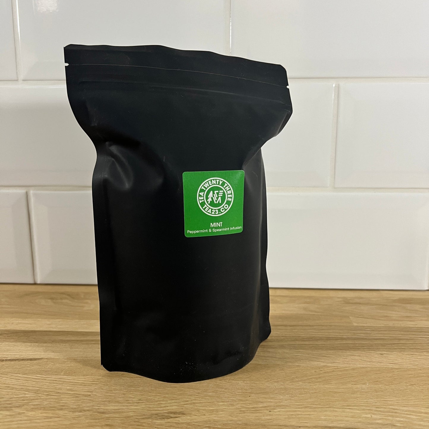 A black pouch of mint tea with a green label on wooden table