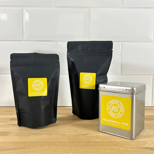 Two black pouches and a silver tin with yellow labels on a wooden surface and tiled wall background.