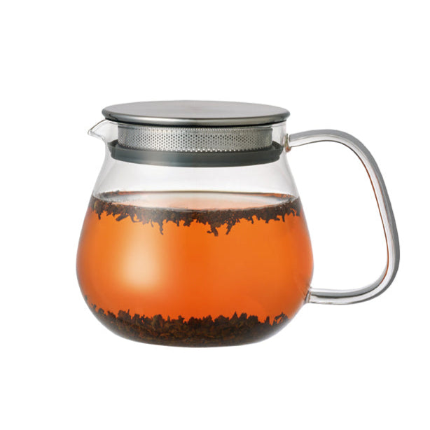 Clear glass teapot brewing tea and stainless steel metal lid on a white background