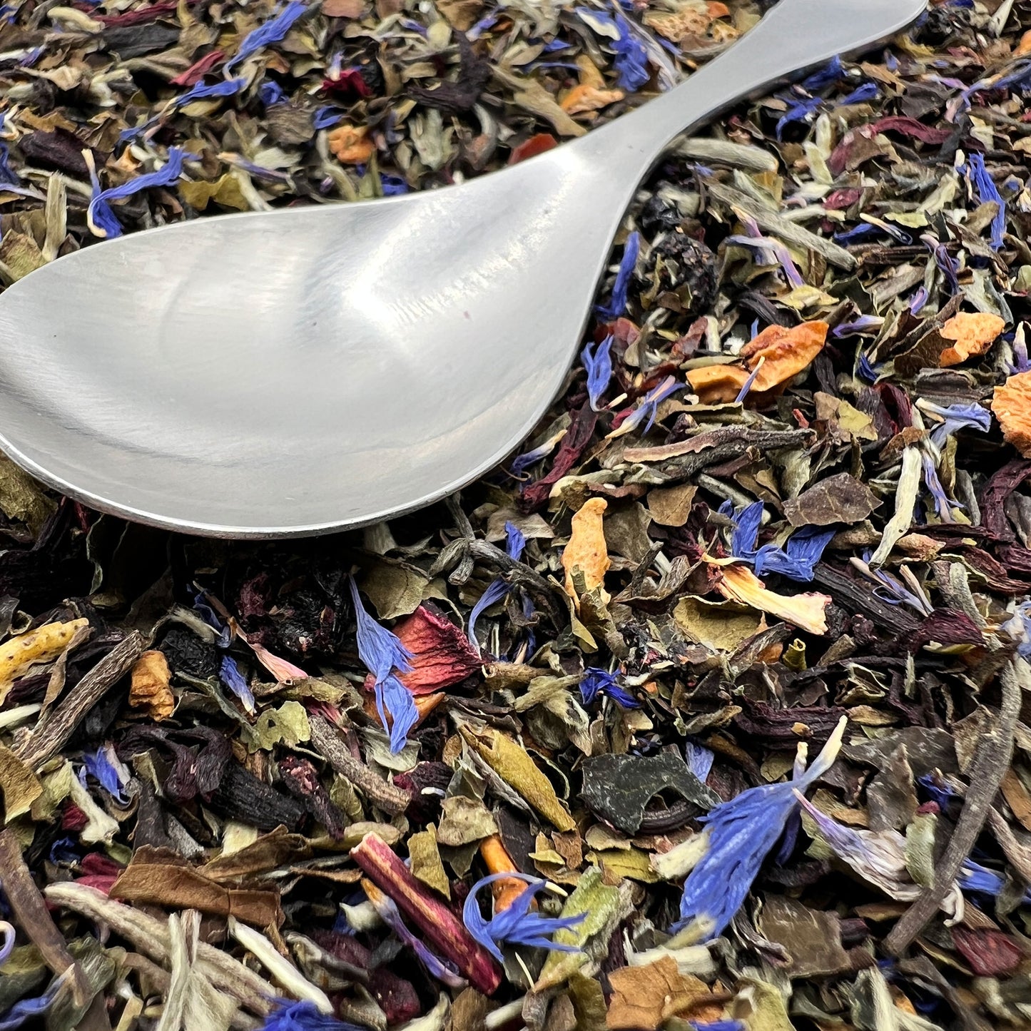 Colorful dried white tea leaves with a silver spoon on top