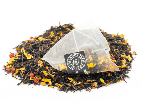 An Aromatic Chai pyramid tea bag from Tea23 sits on top of a pile of loose Aromatic Chai black tea