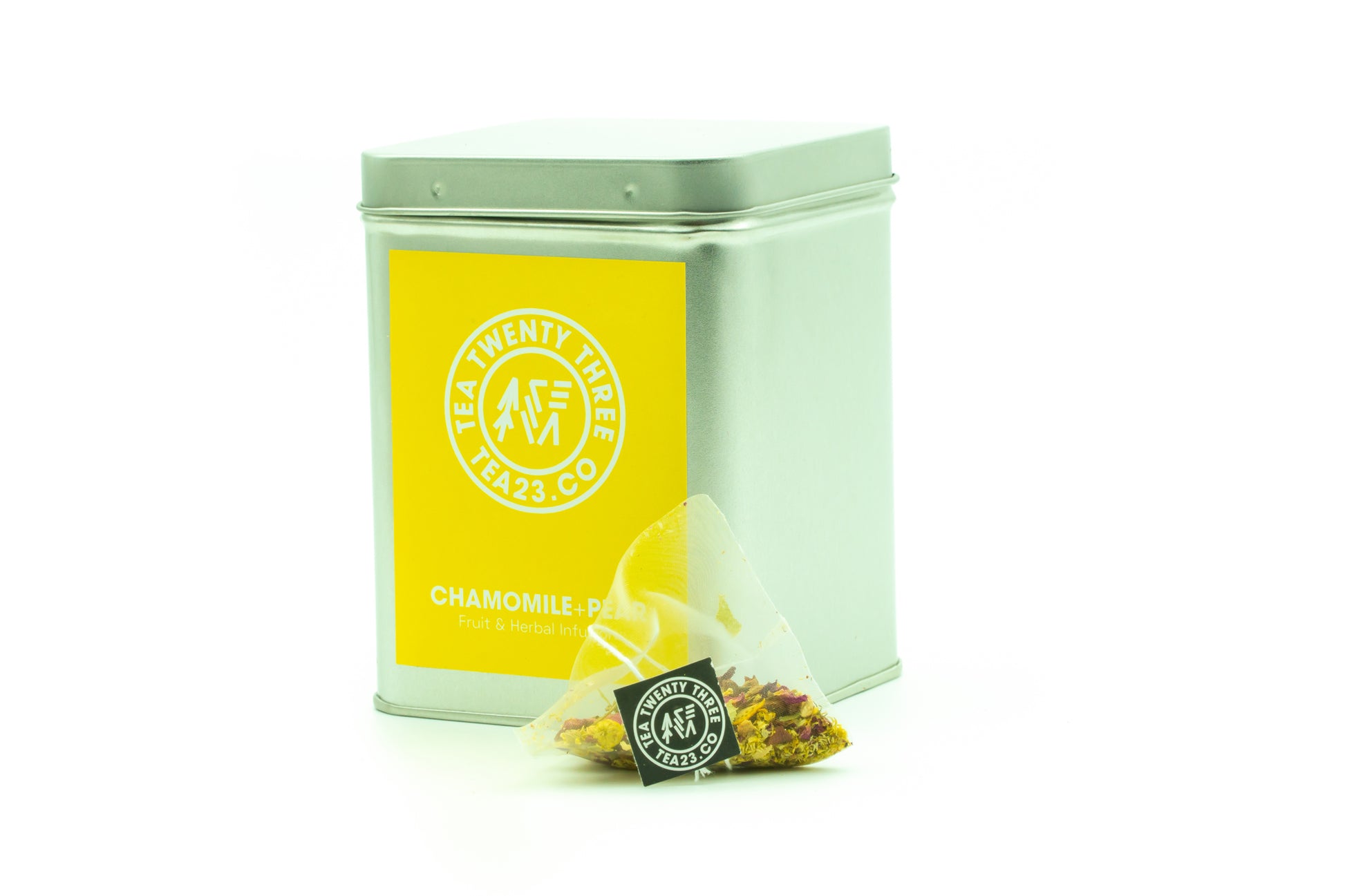 A Chamomile and Pear tea bag from Tea23 sits in front of a Tea23 tea caddy