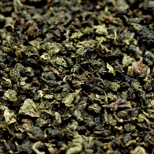 A pile of tightly rolled dark green tea leaves