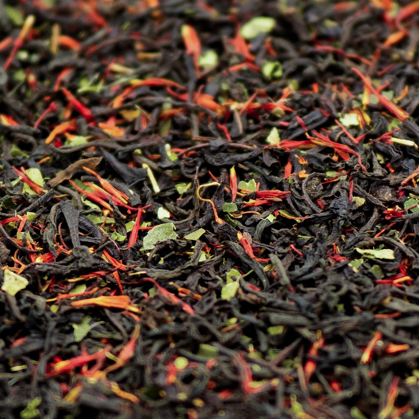 A close up of loose leaf Earl Grey black tea with lime leaves and red safflowers