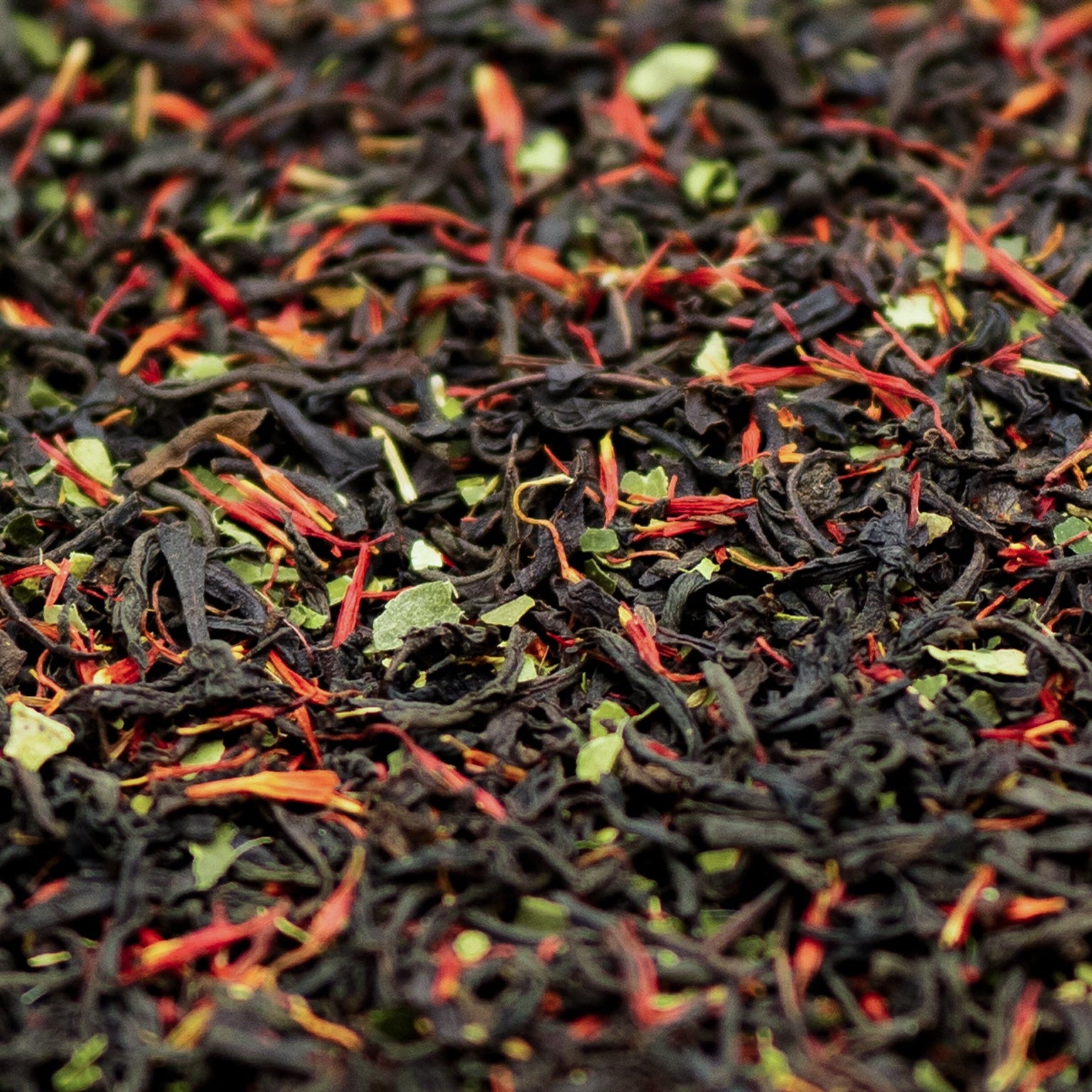 A close up of loose leaf Earl Grey black tea with lime leaves and red safflowers
