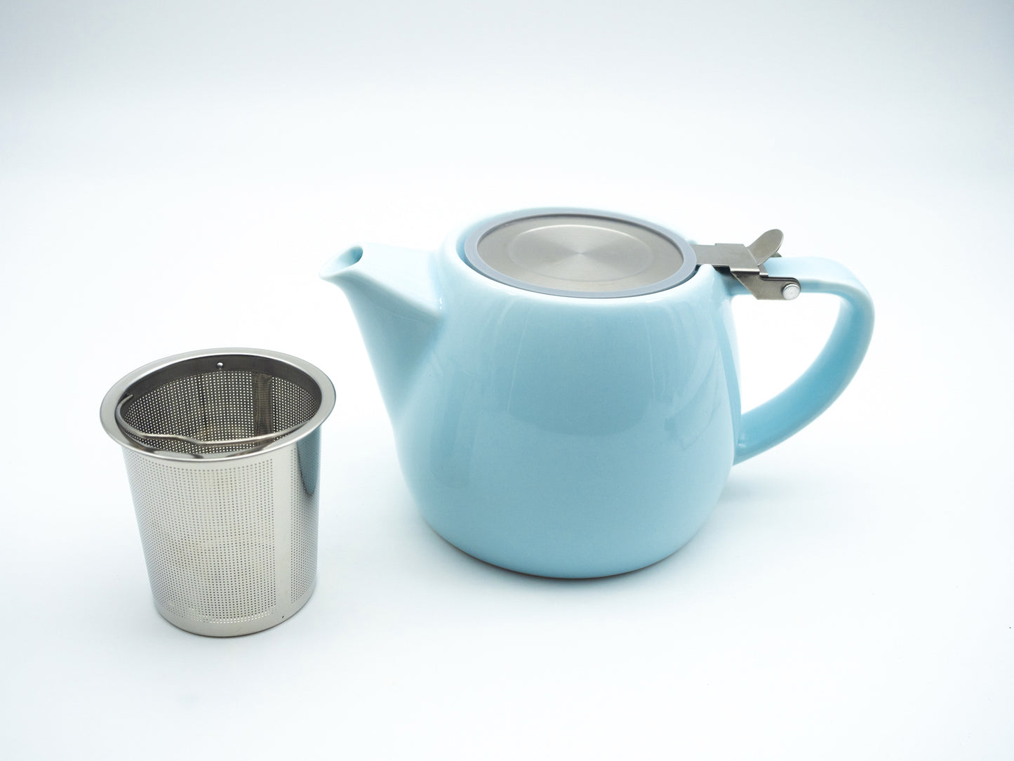 Light blue porcelain tea pot next to a stainless steel infuser basket