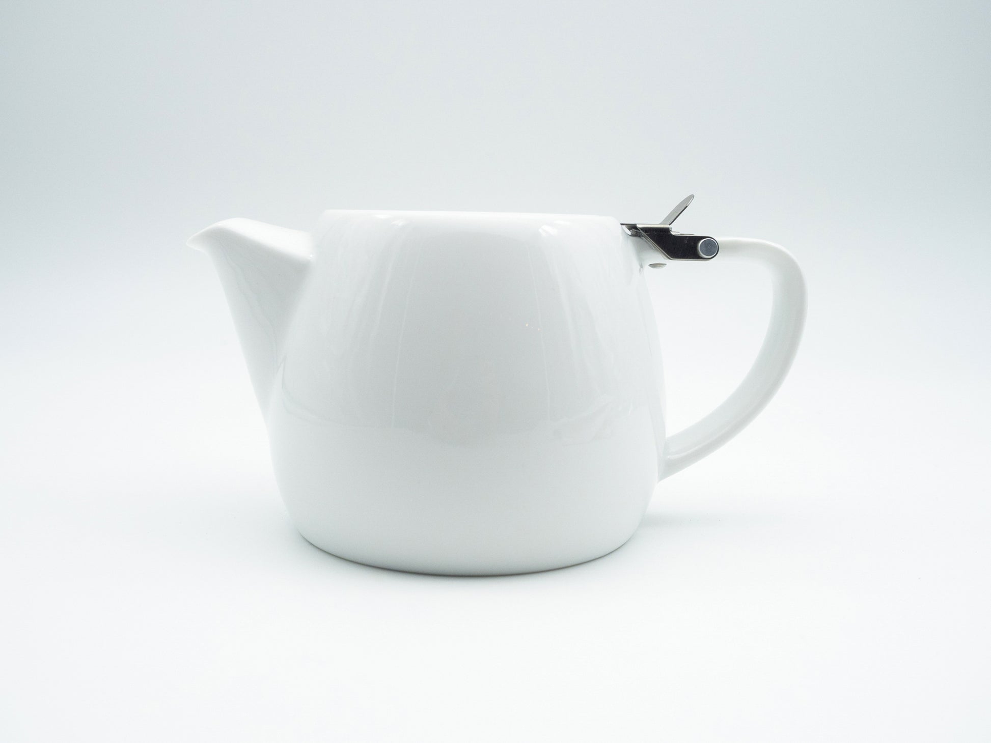 Side view of white porcelain stump tea pot with stainless steel lid and infuser basket