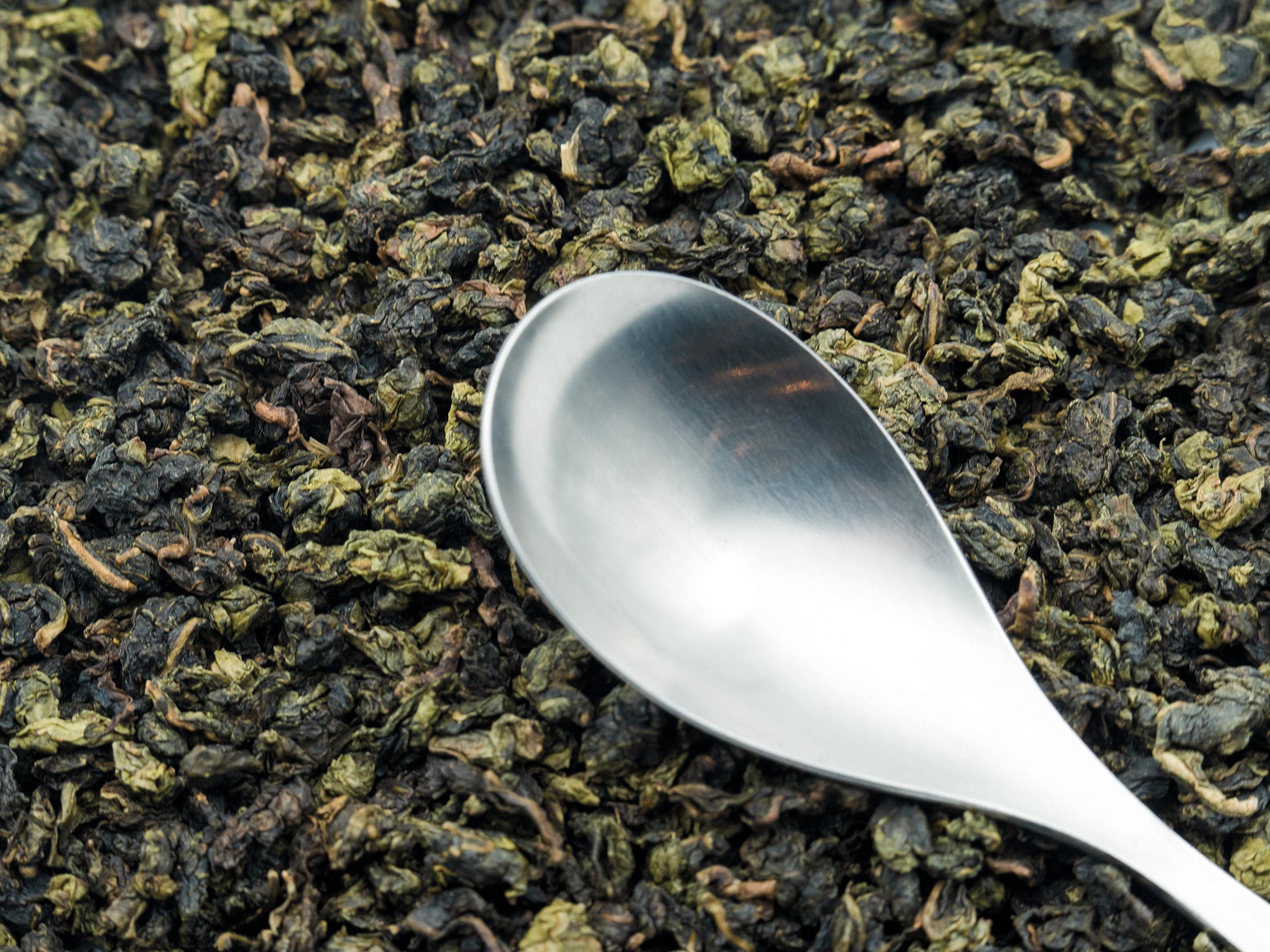 Jade Oolong loose tea from TEA23 with a spoon resting on top
