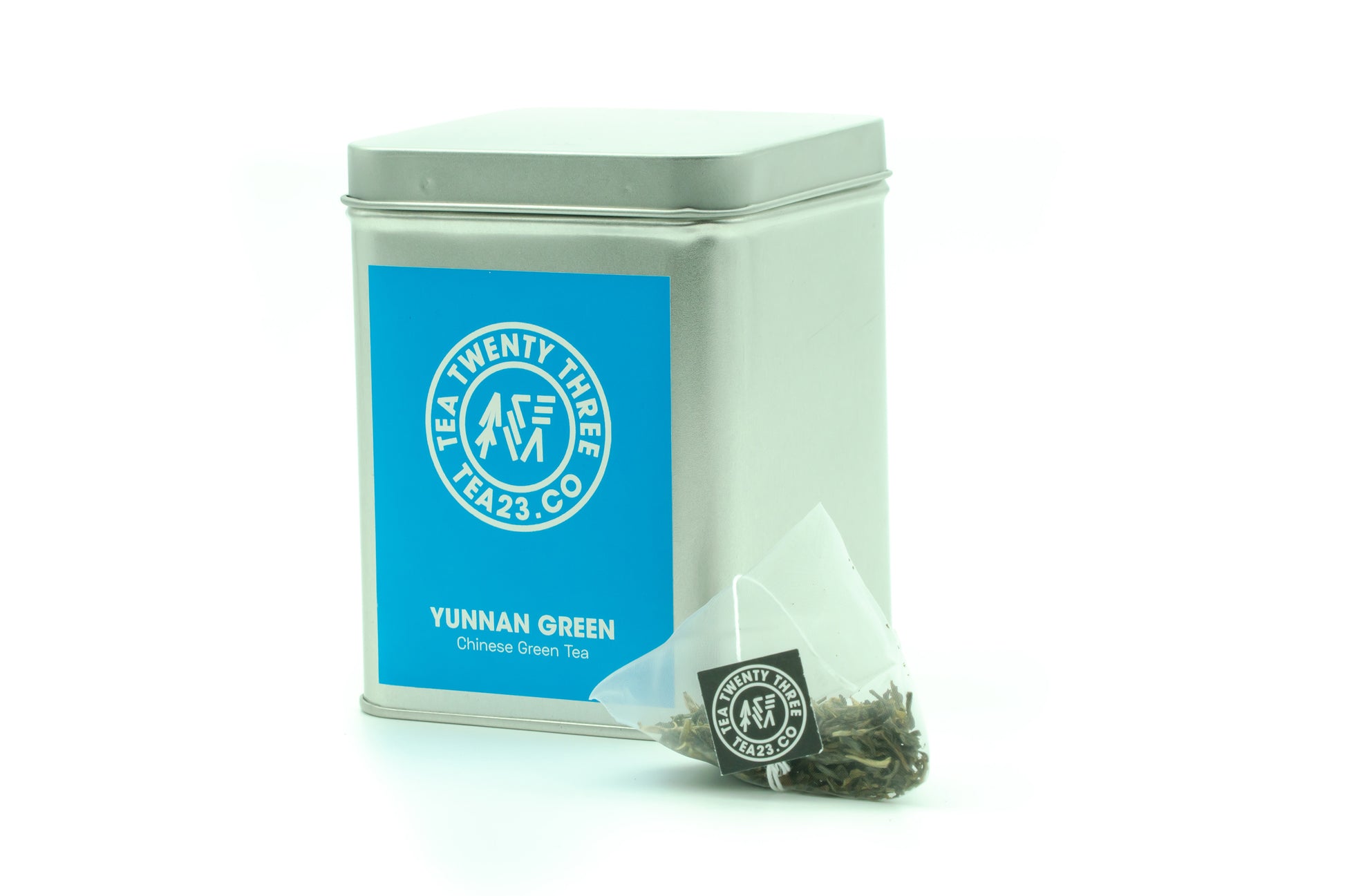 Yunnan green tea in a pyramid tea bag from Tea23 sits in front of a tea caddy
